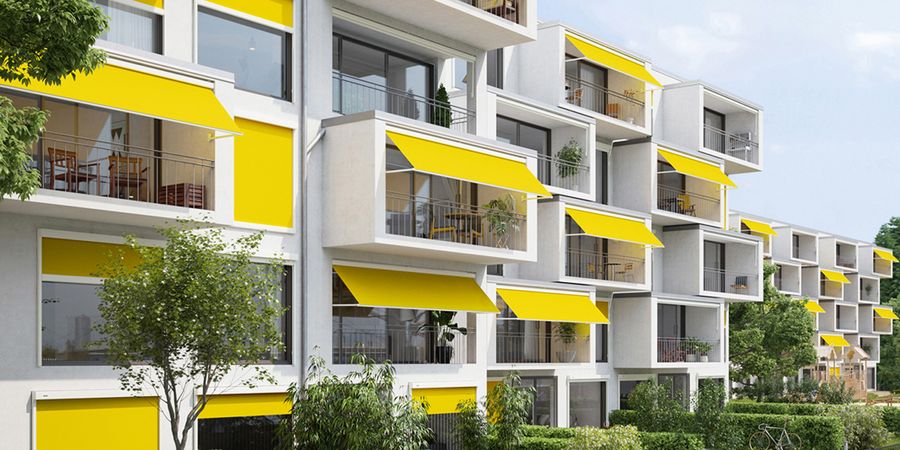 Gelbe Markisen über Balkonen an einem Mehrfamilienhaus.
