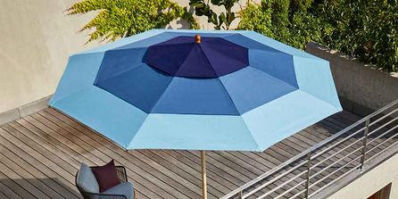 Sonnenschirm mit blauen Streifen auf kleinem Balkon.