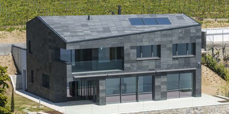 Einfamilienhaus mit Fassade aus Schiefersteinen in symmetrischer Deckung.