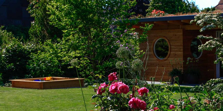 Kleine Sauna aus Vollholz ist in den Garten integriert