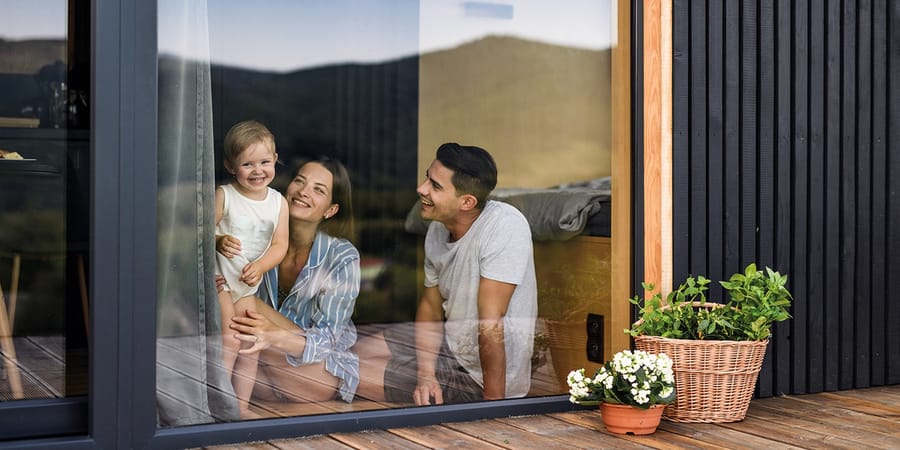 Familie blickt aus einem bodentiefen Terrassenfenster