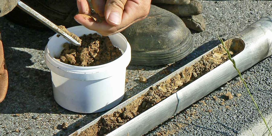 Experte nimmt Bodenprobe für ein Bodengutachten.
