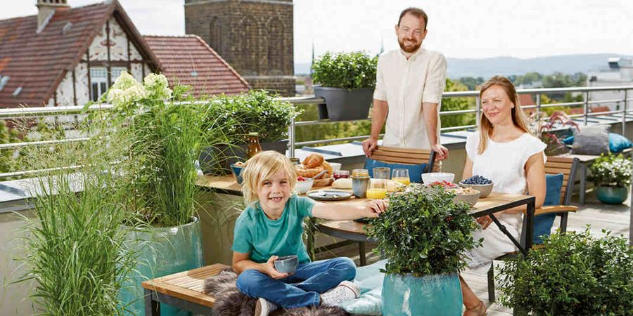 Familie auf einem Balkon mit Kräutergarten