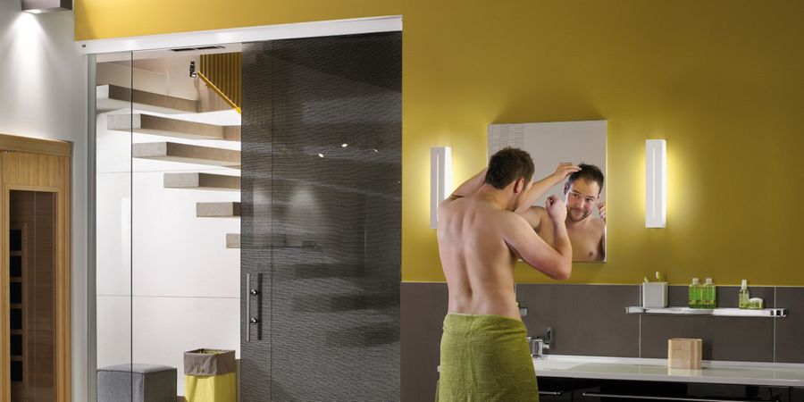 Mann vor Spiegel im Bad mit Licht durch umfangreiche Beleuchtung