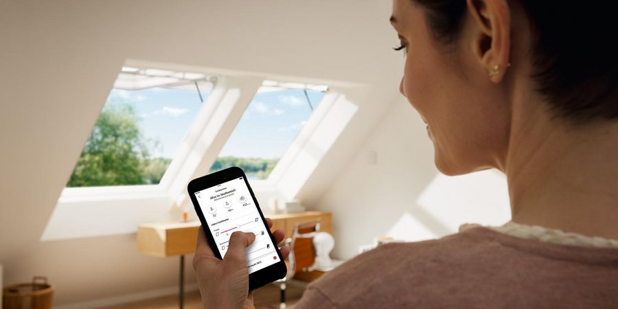 Frau steuert elektrische Dachfenster per Smartphone App. 