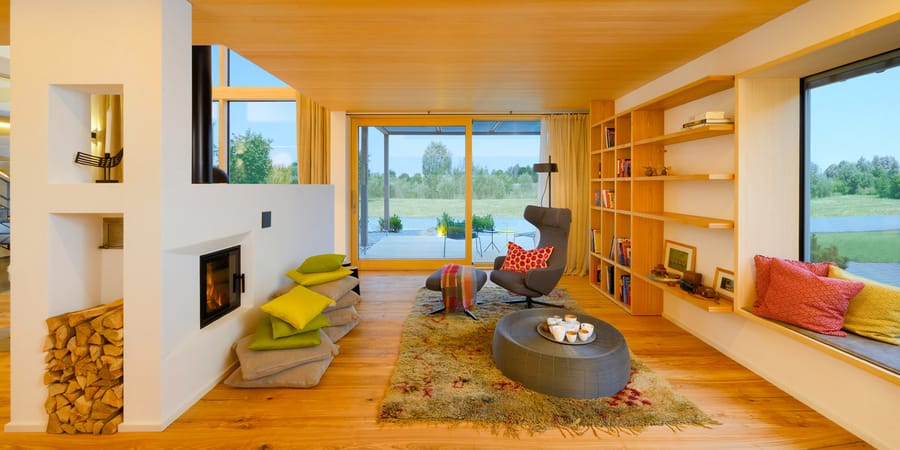 Wohnzimmeransicht mit großflächiger Verglasung und Eschenparkett. Foto: Baufritz