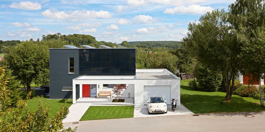 Modernes Einfamilienhaus im Grünen mit PV-Anlage auf Dach und Fassade.