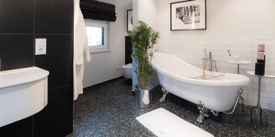 Badezimmer mit freistehender Badewanne, Toilette und Waschbecken in den Farben Schwarz und Weiß gehalten