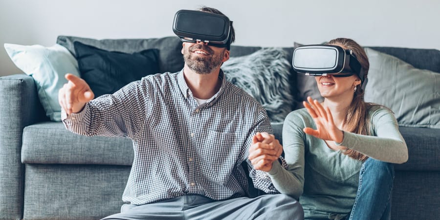 Mann und Frau mit Virtual-Reality-Headsets im Wohnzimmer