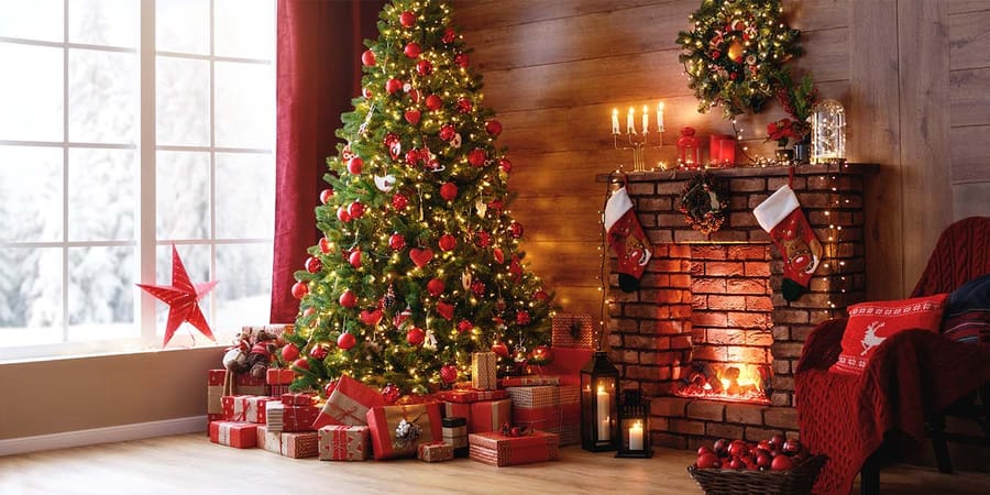 Kerzen und Weihnachtsbaum an Weihnachten vor einem Kaminfeuer