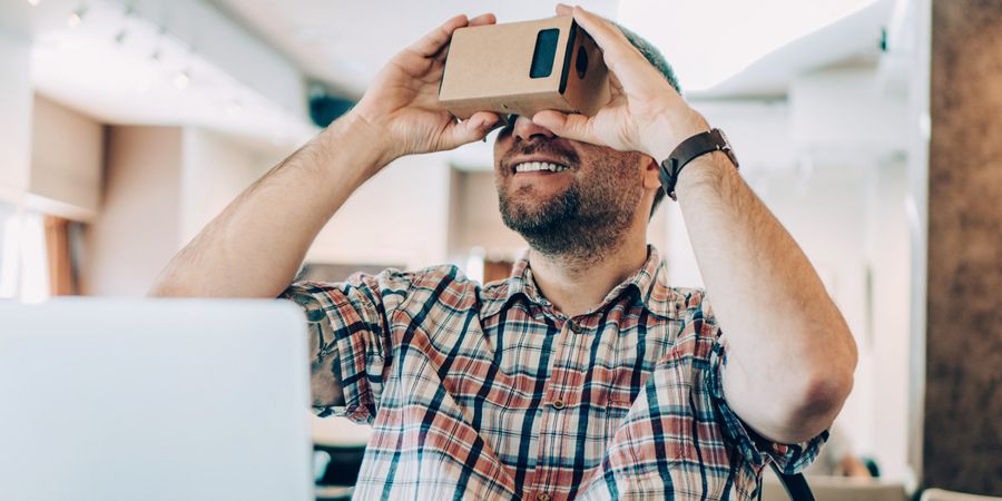 Mann mit Cardboard und Smart Phone betrachtet Virtual Reality