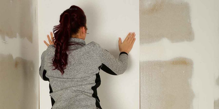 Frau tapeziert eine Wand selbst