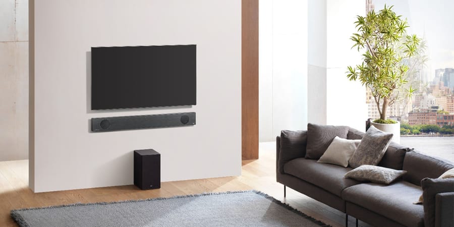 Fernseher mit Soundbar an der Wand in einem Wohnzimmer montiert.