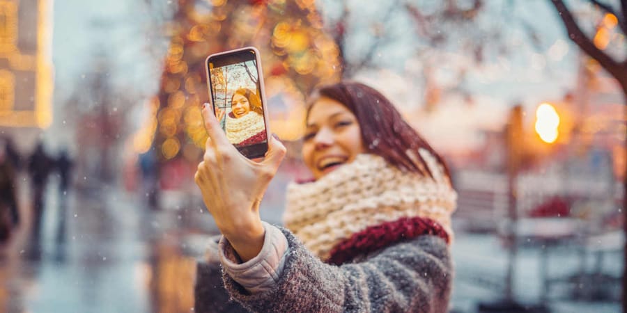 Frau macht im Urlaub ein Selfie und schickt es an Freunde und Familie.