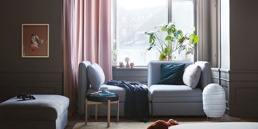 Wohnzimmer mit Sofa und vielen Kissen in gedeckten Farbtönen