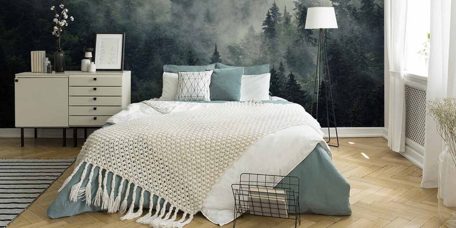 Fototapete mit nebeligem Wald hinter gemütlichem Bett