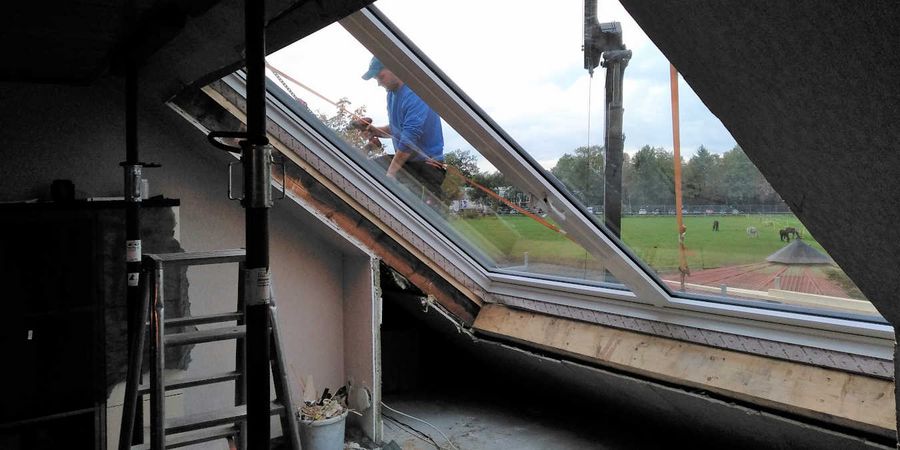Handwerker baut Dachschiebefenster ein.