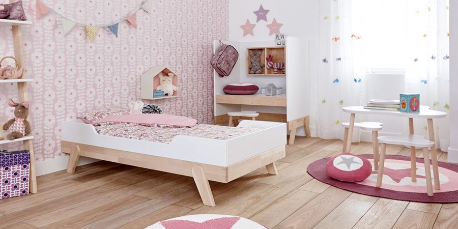 Bett in einem rosafarbenen Kinderzimmer.