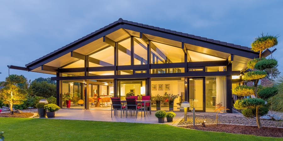 Der luxus Bungalow von HufHaus bietet dank moderner Fachwerkbauweise eine große Glasfront zum Garten hin. Das Satteldach sorgt zudem für hohe Decken.