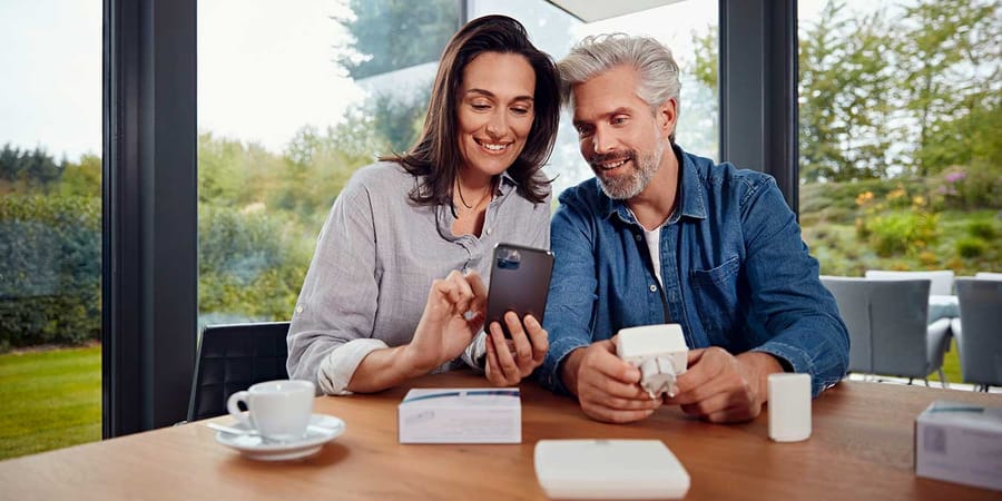 Paar richtet Smart Home am Smartphone ein.