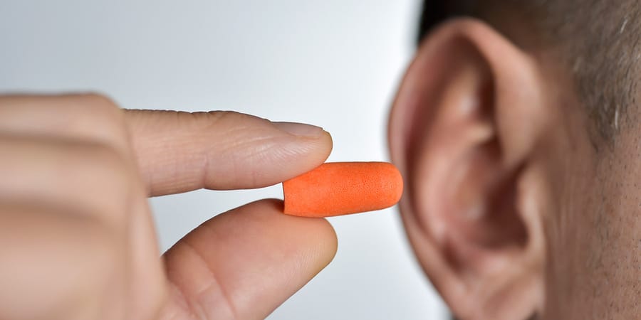 Stöpsel-Gehörschutz wird von einem Mann in sein Ohr gesteckt