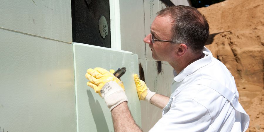 Fachmann bringt Polystyrolplatten zum Schutz der Außenabdichtung an.