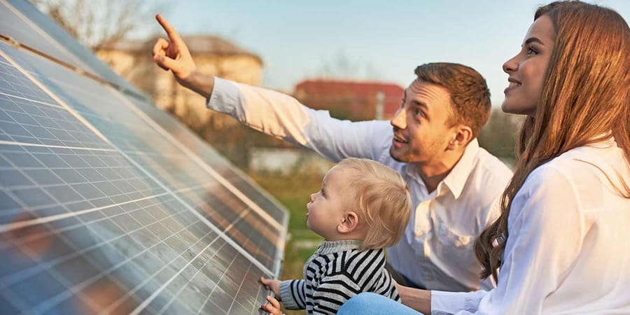 Junge Familie begutachet Photovoltaikanlage auf dem Dach