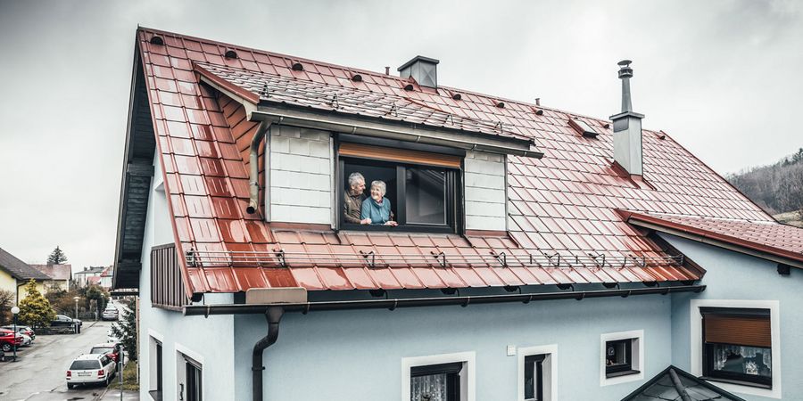Älteres Ehepaar blickt aus Dachfenster im Aluminiumdach 