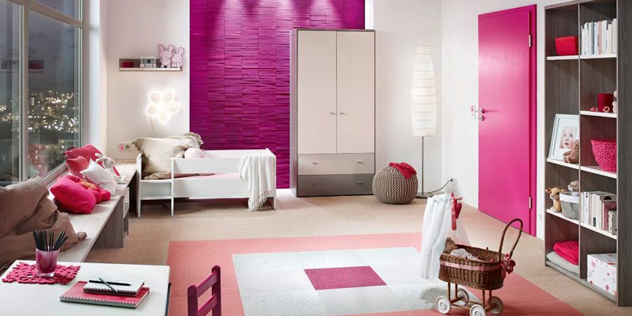 Kinderzimmer mit weißen Möbeln und einer pinken Wand und Tür.