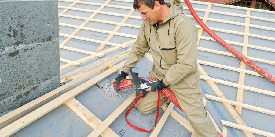 Handwerker bringt Einblasdämmung aus Holzfaser in das Dach ein.