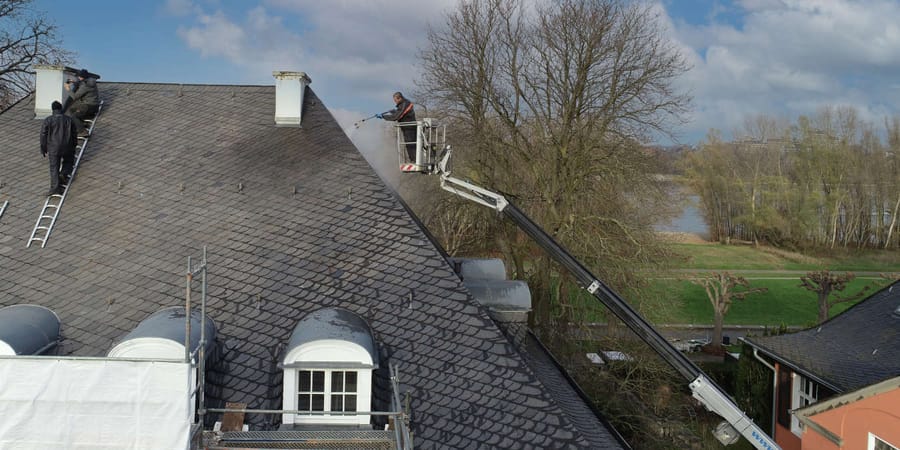 Dachdecker suchen das Dach nach Schäden ab.