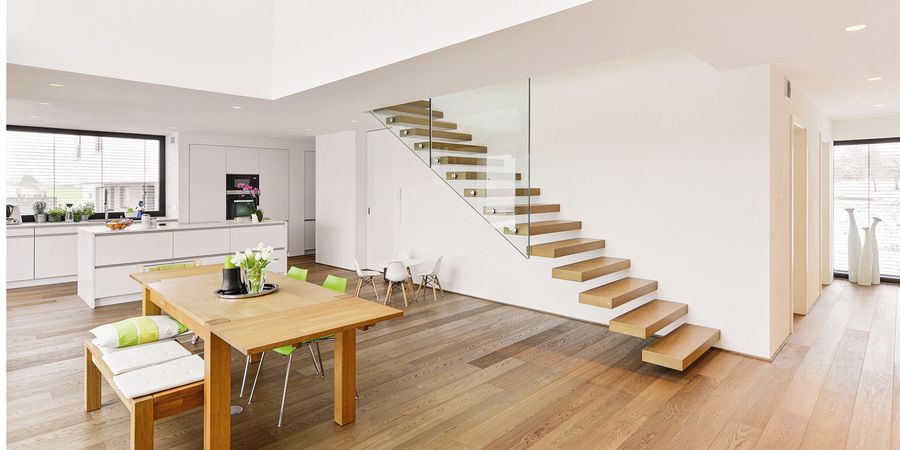 Moderne Holztreppe mit Glasgeländer in hellem Einfamilienhaus.