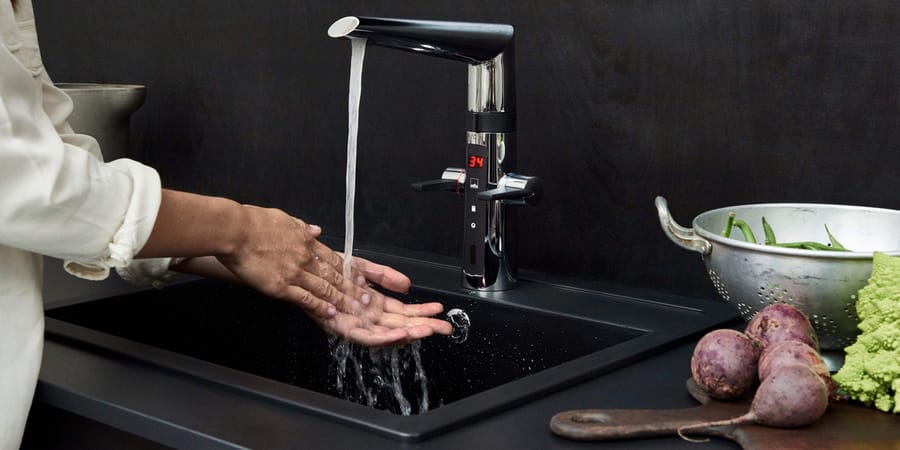 Frau wäscht sich Hände an Küchenarmatur