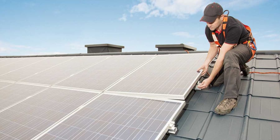 Fachmann installiert Photovoltaikanlage auf dem Dach eines Einfamilienhauses