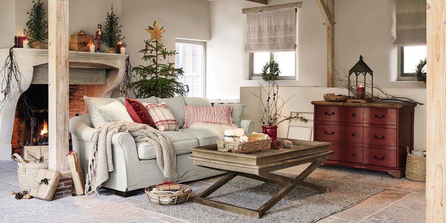 Weihnachtlich dekoriertes Wohnzimmer im amerikanischen Landhausstil mit Decken, Kissen und einem Kamin.