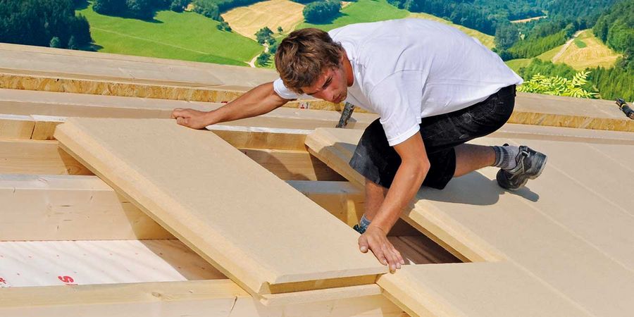 Handwerker legt Dachdämmung aus Holzfaserplatten