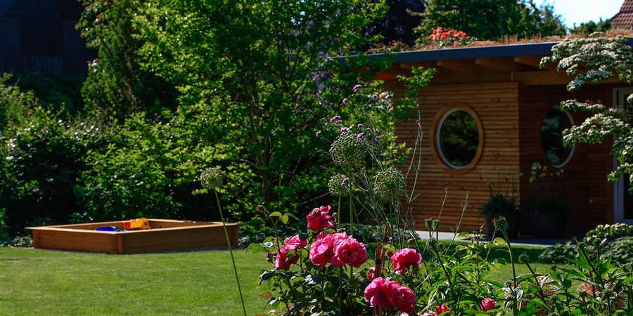 Kleine Sauna aus Vollholz ist in den Garten integriert