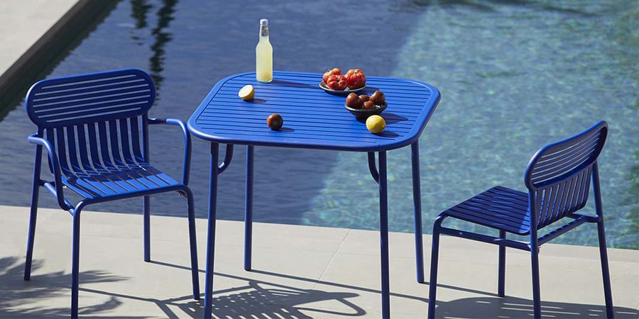 Blaue Gartenmöbel an einem Pool.