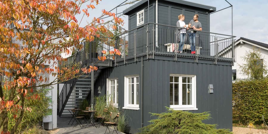 Graues Tiny House aus einem FlyingSpace Modul mit Dachgarten, Terrasse und kleinem Gerätehäuschen