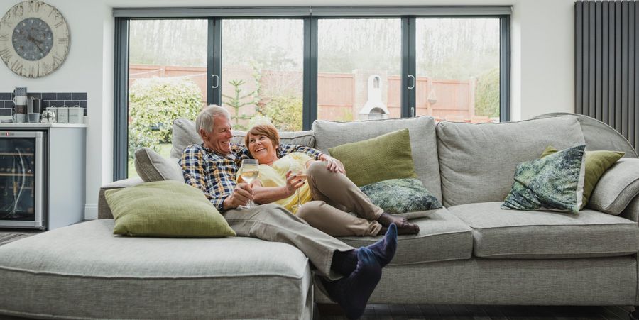 Älteres Ehepaar auf einer Couch im hellen Wohnzimmer.