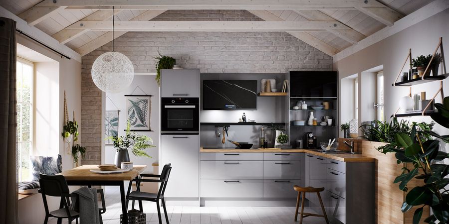 Zentrales Element des Innenausbaus: Die graue Küche verfügt über eine Arbeitsplatte in Holzoptik und praktischen Stauraum.