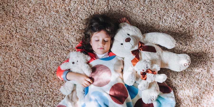 Kind mit Teddybären auf Hochflor Teppich
