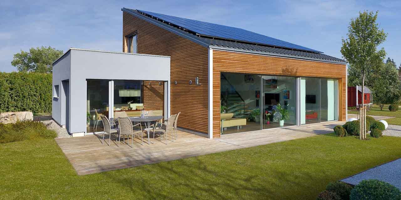 Kleines Haus aus Holz mit Pultdach, Photovoltaikanlage und Terrasse.