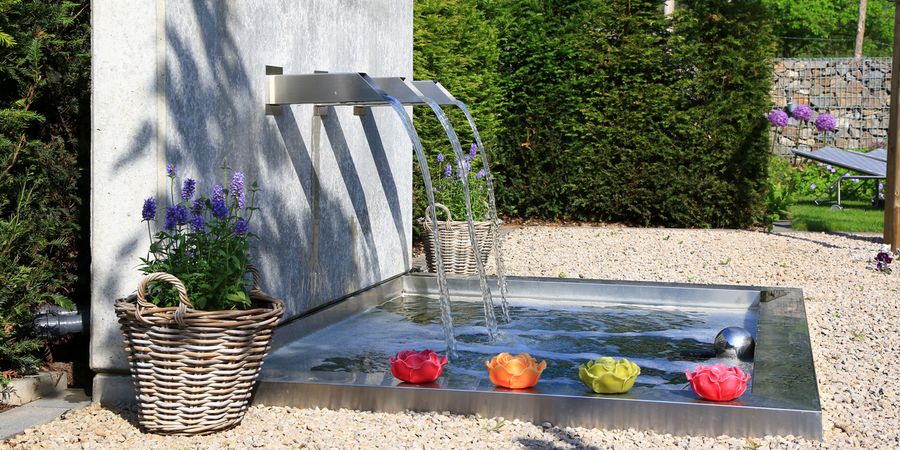 Wasserspiel in einem Garten: Brunnen mit Blumen-Dekoration