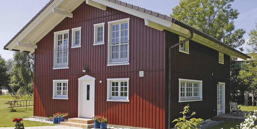 Wohngesundes Holzhaus von außen mit dunkler Holzfassade im schwedischen Baustil.