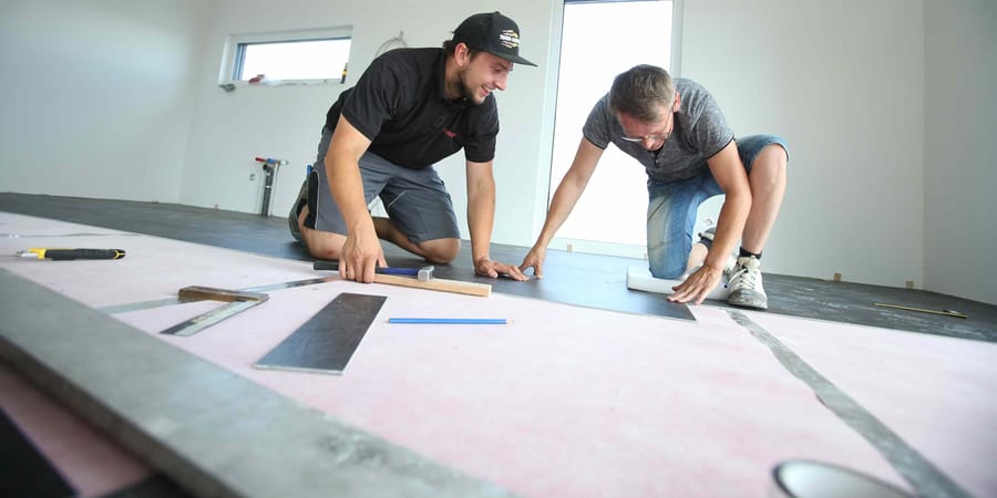 Bauherr und Handwerker verlegen den Vinylboden im Ausbauhaus.