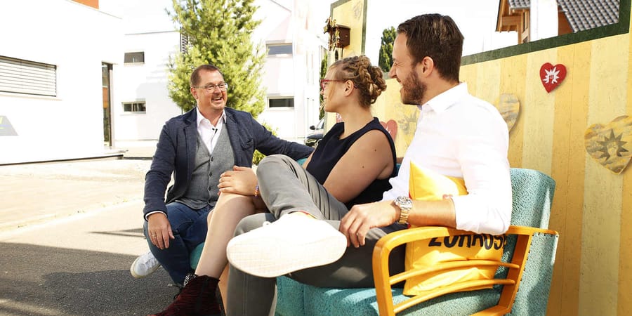 Living Haus Viva la Klartext neues Streaming Format Moderator auf Sofa mit zwei Bauherren als Interviewpartner.