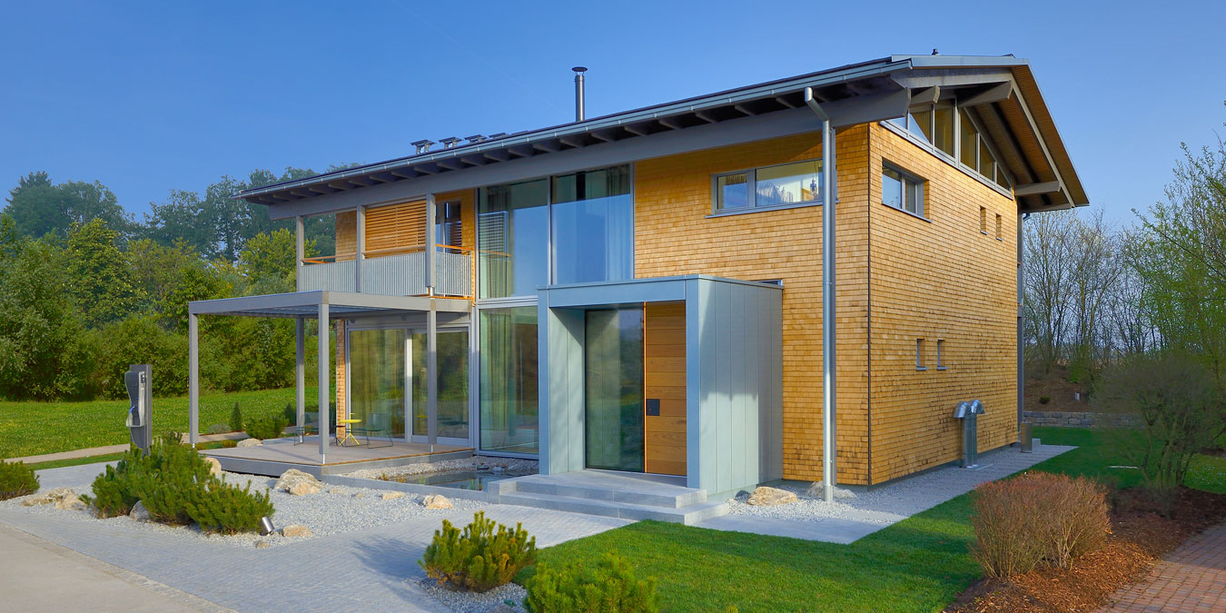 Baufritz - Musterhaus Alpenchic Frontansicht mit großflächiger Verglasung und Schindel-Fassade aus Weisstanne. Foto: Baufritz
