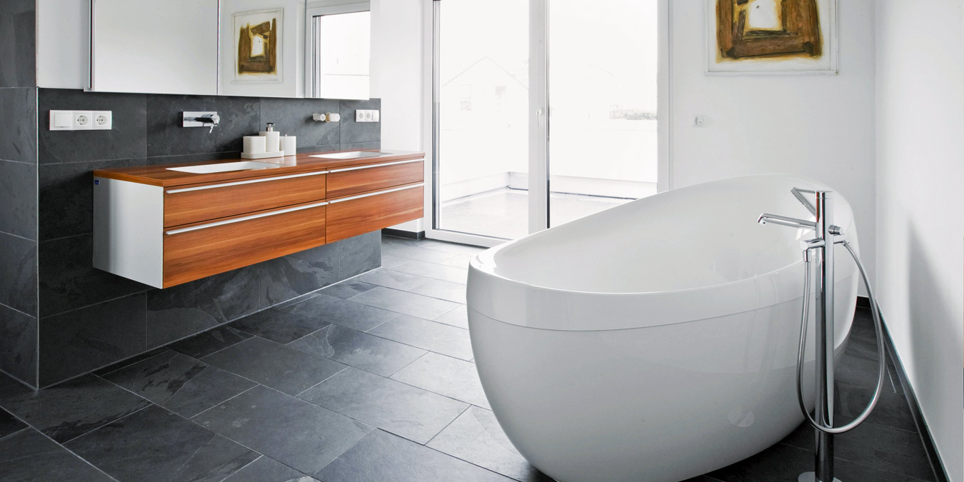 Moderne Badgestaltung: Wände und Boden mit Schiefer verkleidet. Foto: BHW